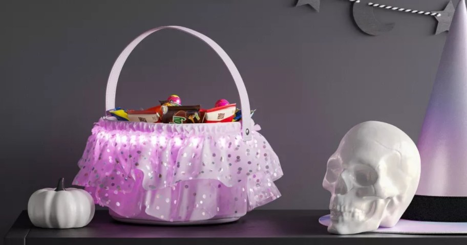 a light purple ruffled trick or treat basket on a table with Halloween decor