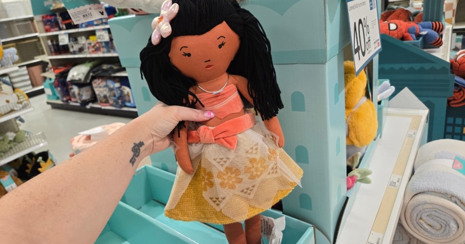 hand holding a plush Moana doll, more Disney items in the background at Target