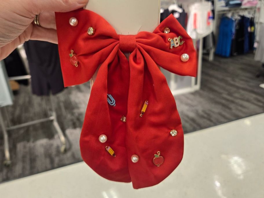 red Teacher Apple Pencil and Pearl Hair Bow Clip in hand in store
