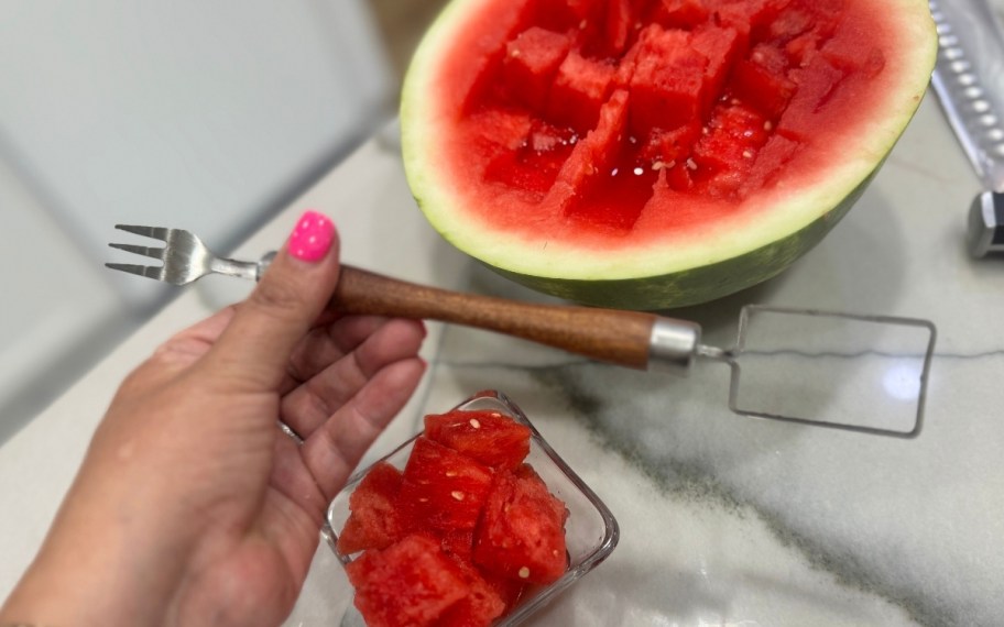 a womans hand holding a dual ended watermelon slicer