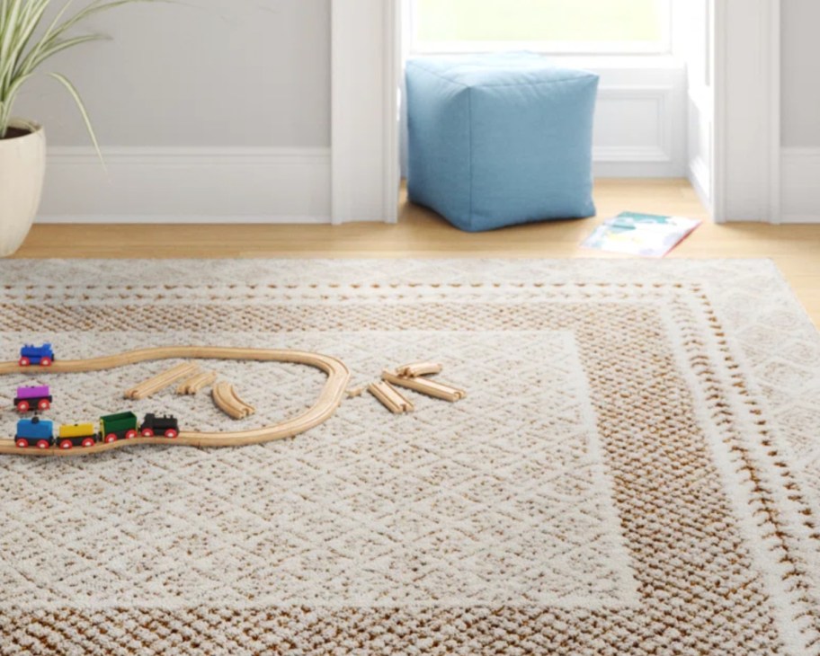 brown woven rug with train track and blue ottoman on it