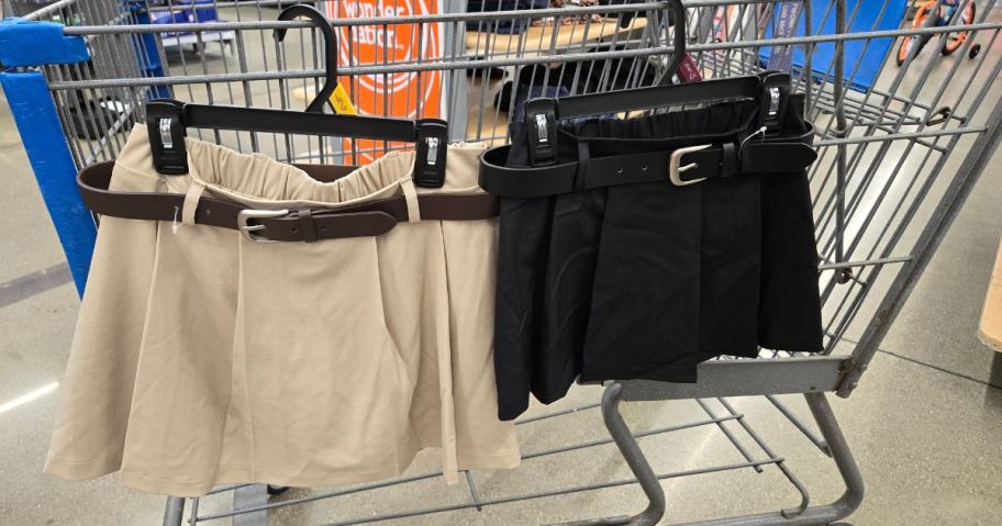 two Weekend Academy Girls Pleated Mini Skirts in beige and black hanging on cart in store