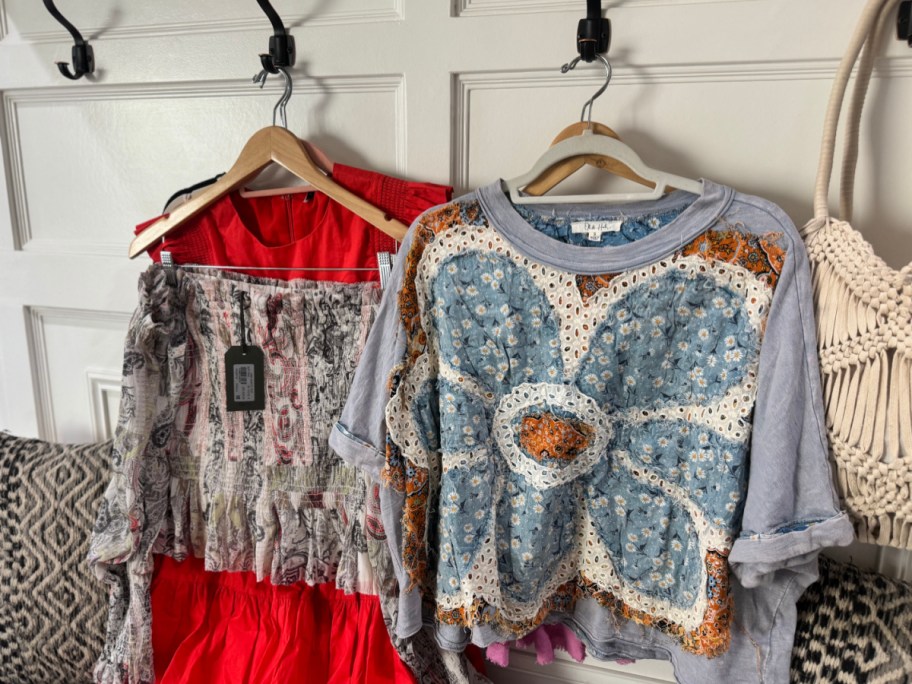 various clothing items hanging on hangers on the back of a door
